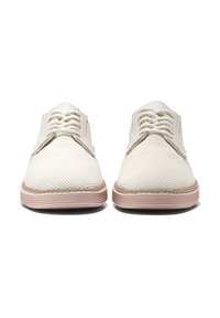 Scarpe bianche in maglia con una superficie testurizzata, dotate di una suola in gomma beige e dettagli rosa chiaro, con un design a laccio anteriore.