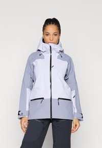 Svetlo siva nepremočljiva jakna s temno sivojimi poudarki. Ima zadrgo na sprednji strani, nastavljivo kapuco in več žepov z zadrgo. Gladek videz.