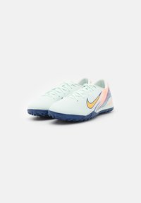 Light blue athletic shoes with a textured upper, featuring a contrasting orange swoosh and a dark blue rubber sole. Rounded toe design.