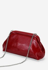 Bolso de mano de cuero sintético rojo con textura arrugada, correa de cadena y diseño gathering, que presenta una forma triangular estructurada.