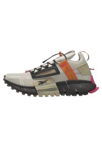 Zapatilla deportiva beige y negra con suela robusta, detalles en naranja y rosa, parte superior de malla y cordones elásticos ajustables con cierre tipo toggle.