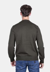 Maglione verde oliva con maniche lunghe e colletto rotondo, realizzato in tessuto a maglia liscia. Presenta un punto vita aderente e un design pulito.