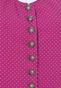 Tela de lunares fucsias con un escote redondo y seis botones decorativos plateados en la parte delantera. Textura suave y patrón uniforme.