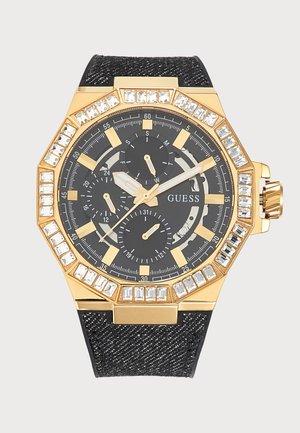 Черно и златно часовник Guess с три малки циферблата, златни часови маркери, безел с кристали и текстурирана черна каишка.