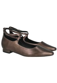 Zapatos planos de bronce metálico con punta en forma de almendra, correas en el tobillo y tacón bajo. Textura suave y diseño minimalista.