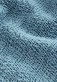 Lys blå strikket tekstil med et struktureret, ribbet mønster. Stofdelen fremstår blød og hyggelig, med synlige fibre og en smidig struktur.