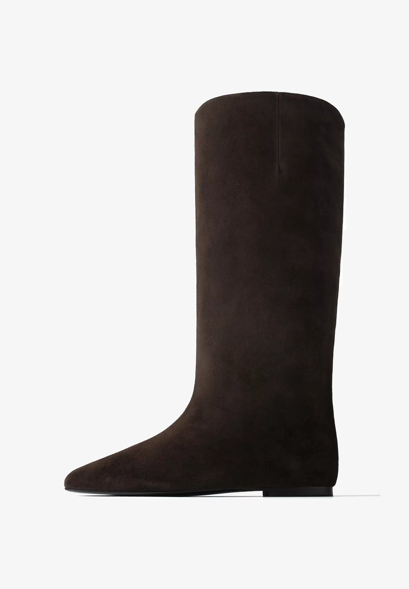 Botte haute en daim noir avec semelle plate et bout arrondi, montrée de côté sur fond blanc.