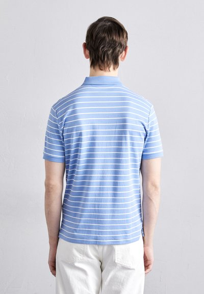 Απαλή μπλε πόλο μπλούζα με λευκές οριζόντιες ρίγες, κοντά μανίκια και γιακά. Φαίνεται να είναι φτιαγμένη από μαλακό βαμβακερό ύφασμα.