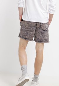 Shorts en délavage marron clair avec un tissu léger. Comprend des coutures visibles, deux poches arrière et un design à jambes droites.