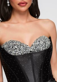 Haut corset noir avec un décolleté en cœur, orné de sequins et perles argentés ; tissu lisse avec de petits motifs à points.