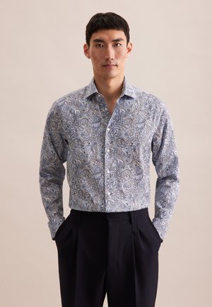 Blauw-wit paisleypatroon shirt met lange mouwen en een button-down kraag, gecombineerd met donkere broek. Katoenen materiaal, casual ontwerp.