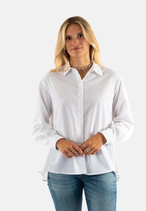 Camisa blanca de manga larga con botón en la parte delantera, cuello clásico y un corte relajado. El tejido parece suave y ligero.