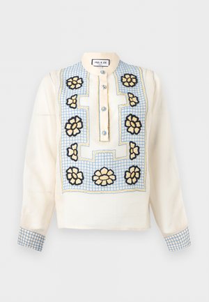 Krém színű hosszú ujjú blúz kék rácsmintával, sárga és fekete virágos hímzéssel az elején és az ujjmandzsettán, valamint kék gombokkal a rövid gombsoron.