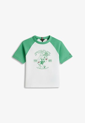 Camiseta blanca y verde con mangas raglán que muestra a un perro de dibujos animados girando un balón de baloncesto, con el texto "Tommy 1985 The Buzzer Beater".