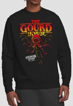 Schwarzer Pullover mit rotem und gelbem Schriftzug "The Gourd Horde" und einer roten, monströsen Pflanzenkreatur aus Stranger Things Tales from the Upside Down.