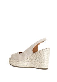 Beige kilklackssandal med en texturerad tygöverdel, öppen tå, slingback-design och en flätad juteplattform.