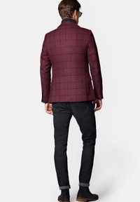 Burgundowy blazer w kratę o dopasowanym kroju, z klapami w kształcie notcha i dwoma guzikami, zestawiony z czarnymi dżinsami i czarnymi botkami za kostkę.