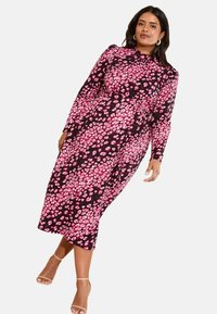 Vestido de manga larga en negro con un estampado de manchas rosas, con una cintura ajustada y longitud midi. Tejido suave con una textura lisa.
