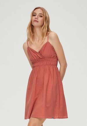 Robe rouge-rosée avec un design enroulé, bretelles spaghetti réglables, taille smockée et jupe fluide. Tissu texturé pour un aspect doux.