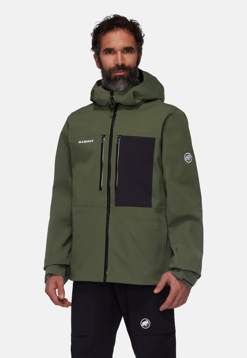 Veste verte imperméable avec capuche, zip avant et poche poitrine noire. Comprend un logo sur la manche et un tissu texturé.