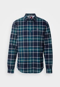 Camisa de franela a cuadros en azul marino con acentos en verde y blanco, cuello abotonado, botones en la parte frontal, y un pequeño logo en el lado izquierdo del pecho.