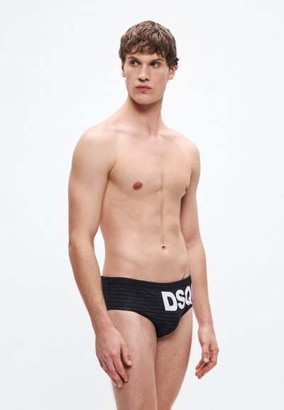 Μαύρο μαγιό σλιπ με υφή σχεδίου και έντονο λευκό λογότυπο "DSQ" στη μέση, κατασκευασμένο από λεία, ελαστική ύλη.