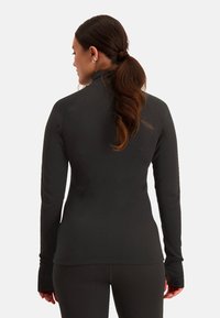 Zwarte lange mouwen sporttop met hoge kraag, naadloos ontwerp en duimopen in de manchetten. Gemaakt van rekbaar, vochtregulerend materiaal.