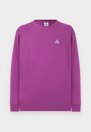 Lila Langarmshirt mit Rundhalsausschnitt, kleinem weißem dreieckigem Logo auf der linken Brust und einem Etikett im Nackenbereich.