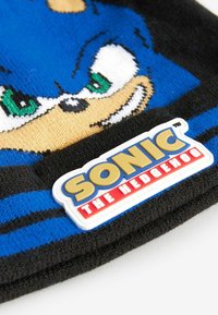Blaue Strickmütze mit dem Gesicht von Sonic the Hedgehog, schwarzen Akzenten und einem weißen Gummilogo-Patch mit roter und gelber Schrift.