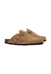 Mules en daim beige avec un bout fermé, une sangle avec une boucle dorée et une semelle en liège. La semelle est texturée pour une meilleure adhérence.