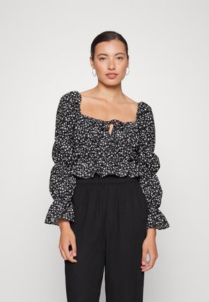 Blusa preta com estampa floral, decote quadrado, mangas bufantes e bainha elástica. Apresenta pequenos padrões florais brancos e rosas. Textura de tecido suave.