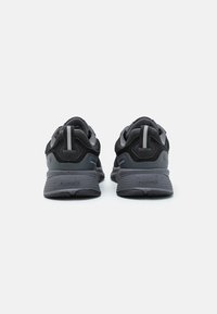 Zapatillas deportivas en negro y gris con parte superior de malla, collar acolchado y suela de goma texturizada con una silueta robusta.