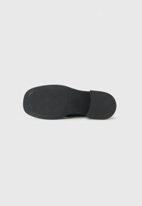 Black shoe sole made of rubber, featuring a smooth surface with a textured grip pattern and rounded toe design.
