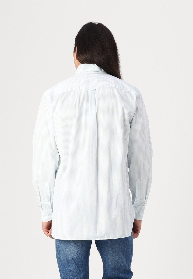 Camicia button-up a righe blu chiaro con maniche lunghe, realizzata in un tessuto leggero, caratterizzata da una spalla posteriore e un orlo leggermente curvo.