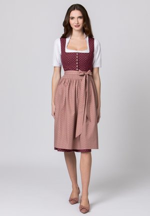 Traditionelle bayerische Tracht mit einem bordeauxfarbigen Polka-Dot-Oberteil, einer weißen Bluse und einem gefältelten rosa Rock mit feinen vertikalen Streifen und einer Schleife.