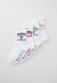 Vier paar witte katoenen sokken met de merknaam "TOMMY" en "SINCE 1985" in contrasterende kleuren: marineblauw, rood, groen en beige.