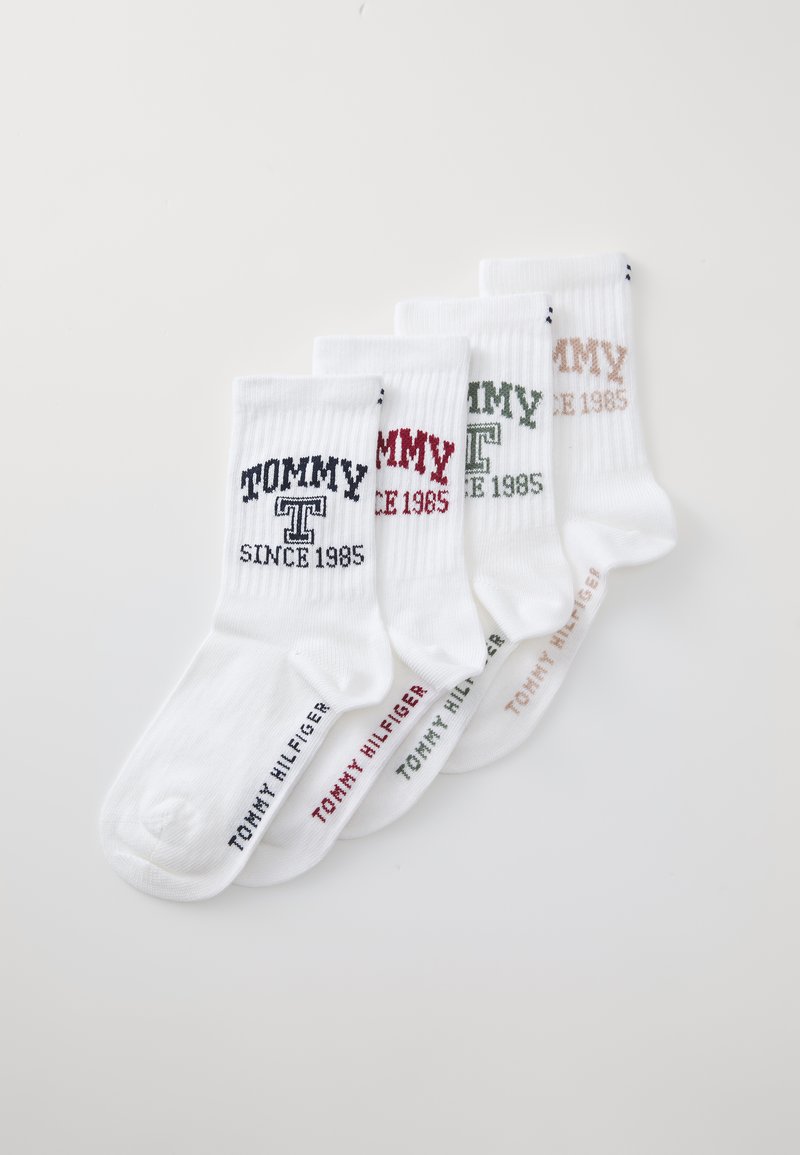 Quatre paires de chaussettes en coton blanc arborant le nom de la marque "TOMMY" et "SINCE 1985" dans des couleurs contrastées : marine, rouge, vert et beige.