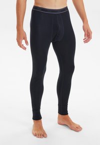 Black thermal leggings made of a stretchy, soft fabric with a fitted design. Features a branded waistband and ankle cuffs.