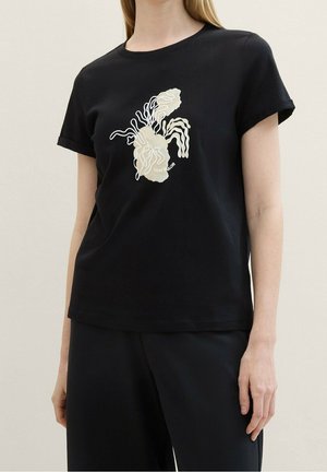 Sort bomulds-T-shirt med hvidt abstrakt design på fronten, rund halsudskæring og korte ærmer. Glat tekstur og afslappet pasform.