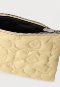 Žlté kožené puzdro s reliéfnym kvetinovým vzorom, so zipsovým zatváraním a čiernym vnútrom. Hladká textúra s jemnými švami.