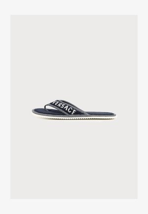 Mørkeblå flip-flop sandal med hvid sål og teksturerede stropper med delvist synligt brandnavn "Versace" i hvide bogstaver.