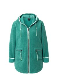 Veste en polaire turquoise avec une fermeture éclair sur le devant, une capuche, deux poches latérales zippées et des bordures blanches. Texture douce et coupe oversize.