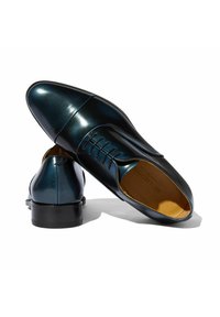 Zapatos oxford de cuero pulido en negro y azul, con puntera afilada, diseño de cordones y tacón bajo apilado. Textura suave y costuras mínimas.