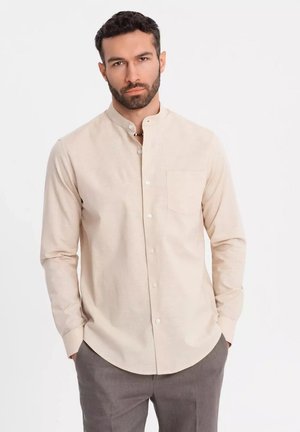 Beige long-sleeve shirt with a mandarin collar, single chest pocket, and button front; made of soft fabric with a smooth texture.