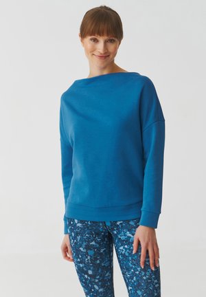 Blue sweatshirt with a boat neckline and loose fit, paired with blue patterned leggings featuring abstract shapes in varying shades of blue.