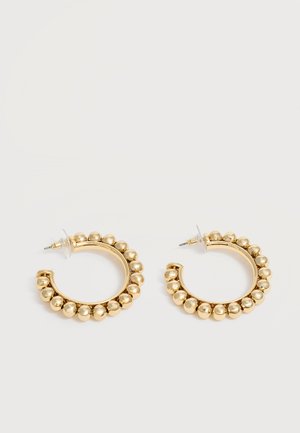 Paire de boucles d’oreilles créoles dorées avec des détails de perles arrondies le long du bord extérieur sur un fond clair.