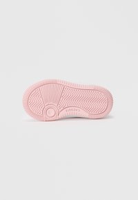 Semelle de basket en caoutchouc rose avec un motif cannelé, un design circulaire près du talon et un détail de marque. Texture lisse et construction plate.