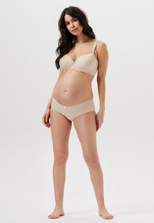 Nude zwangerschapbeha met gladde cups, verstelbare schouderbandjes en een decoratief middenstuk. Bijpassende bikini-hoog uitgesneden slip in dezelfde kleur met een subtiele glans.