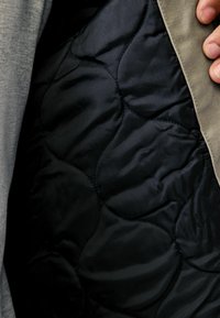 Sisustuksessa on musta tikkikangas, jossa on sileä pinta ja pyöreitä kuvioita. Reunat on viimeistelty vaaleanharmaalla kankaalla.