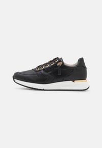 Sneaker in pelle nera con hardware e lacci dorati, caratterizzato da un dettaglio con zip sul lato, suola bianca e texture liscia.